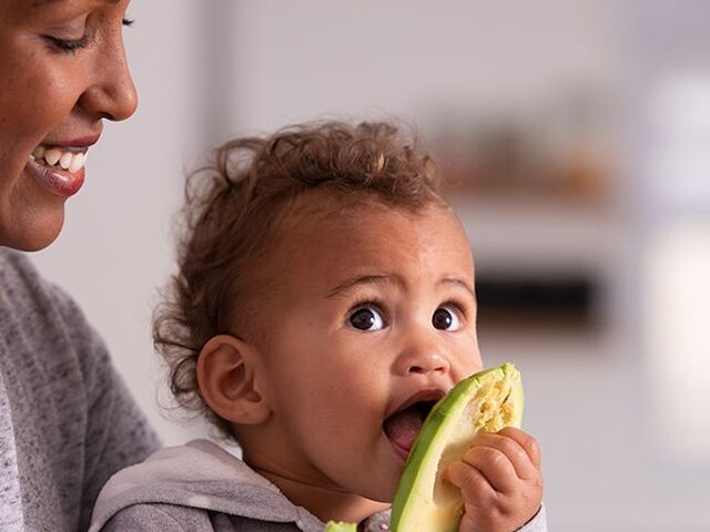 Un bambino mangia da solo un avocado