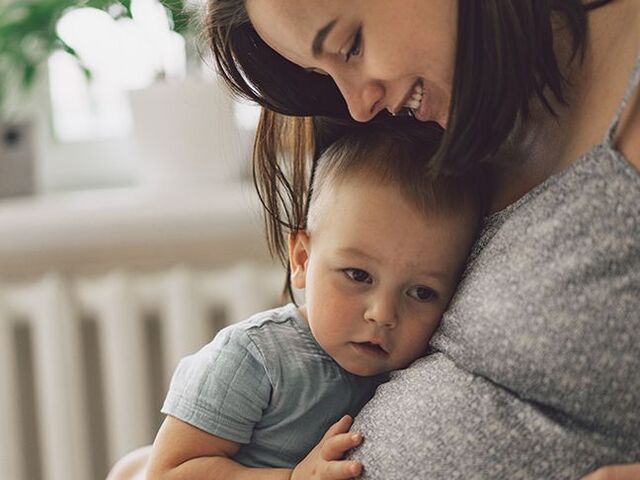 Un bimbo piccolo appoggia la testolina sul pancione della mamma.
