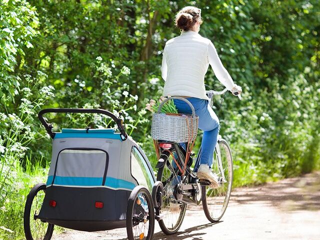 Una madre va in bicicletta con un rimorchio per bici