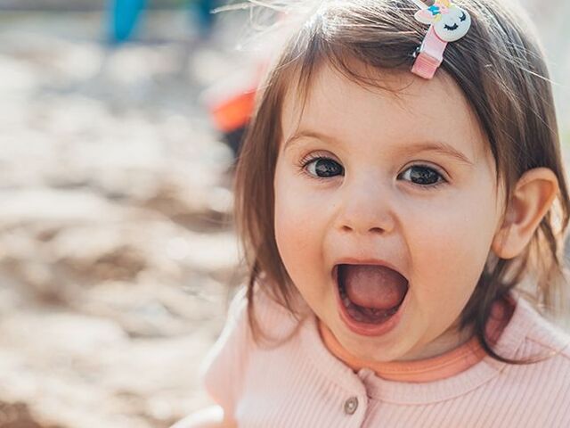 Una bimba piccola guarda l’obiettivo con la bocca aperta.