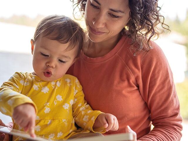 Un bimbo sfoglia un libro con la sua mamma.