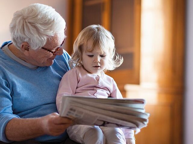 Un nonno sfoglia il giornale con la nipotina.