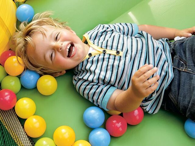 Un bimbo che ride in una vasca di palline.