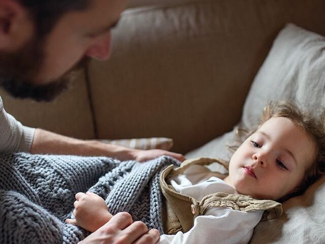 Un papà accarezza il suo piccolo a letto ammalato.