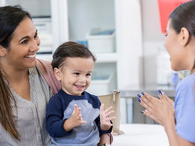 Un bimbo piccolo in grembo alla mamma in ospedale gioca con la pediatra