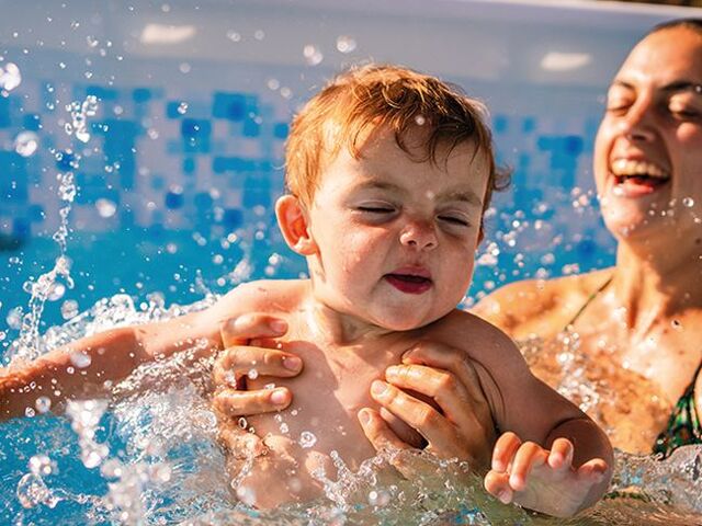Una mamma fa il bagno in piscina con il suo piccolo.