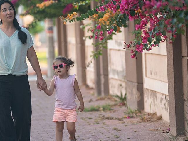 Una mamma cammina con la sua bimba sul marciapiede