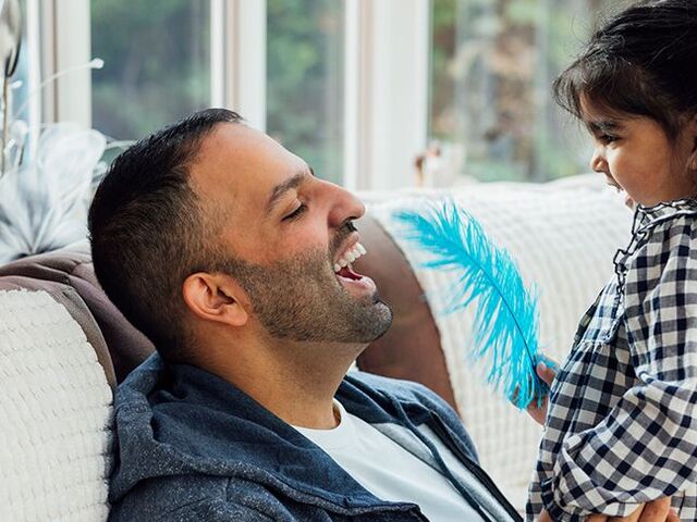 Una bimba gioca con una molla blu insieme al papà.