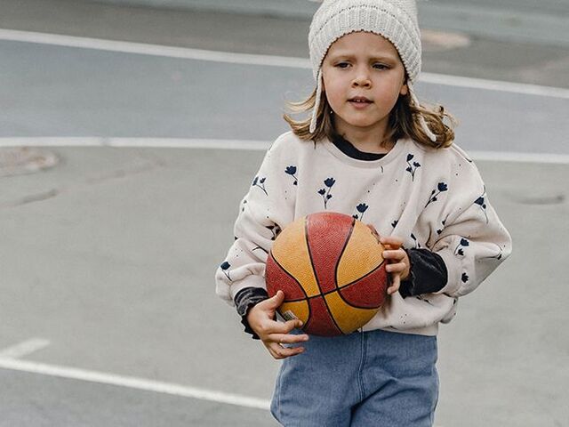 Un bimbo con un pallone da basket in mano.