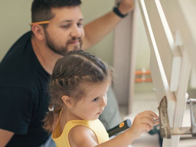 Un papà monta un letto a soppalco insieme alla figlia.