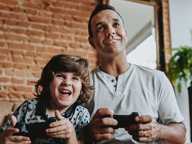 Un bimbo e il suo papà impegnati in un videogioco.