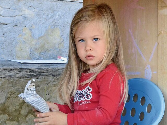 Una bimba seduta su una sedia in plastica.