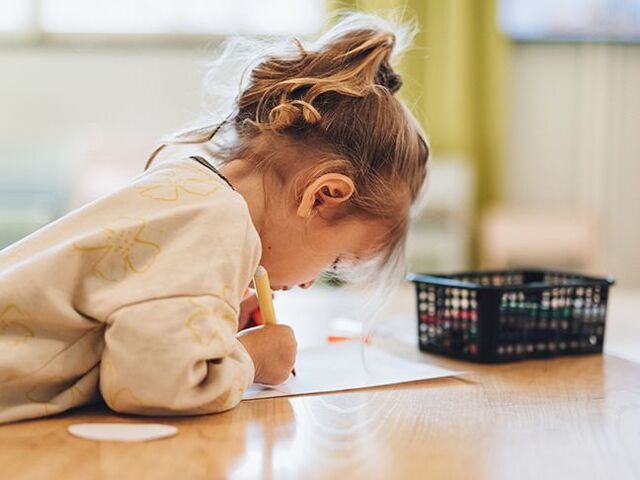 Una bimba dipinge su un foglio di carta.