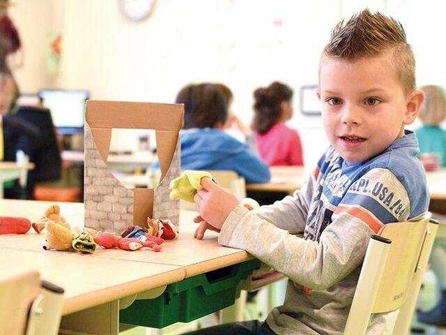 Un bimbo fa dei lavoretti in una classe.