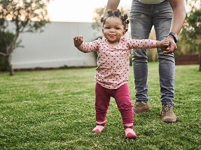 Un bambino di un anno dà la mano al suo papà.