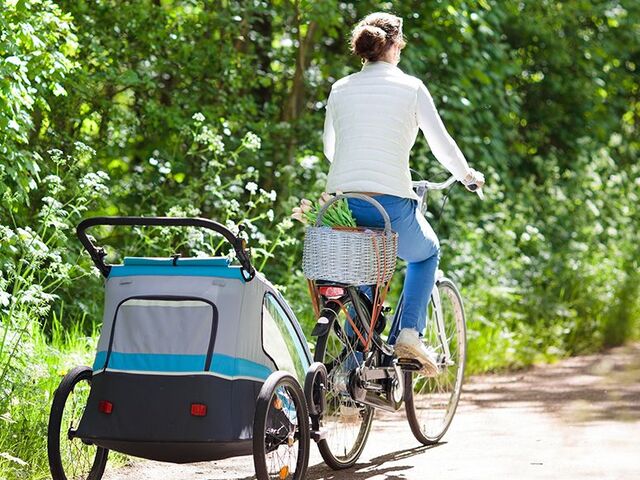 Una madre va in bicicletta con un rimorchio per bici