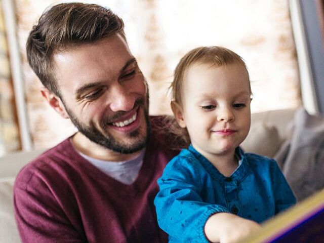 Un bimbo piccolo sfoglia un libretto con il papà.