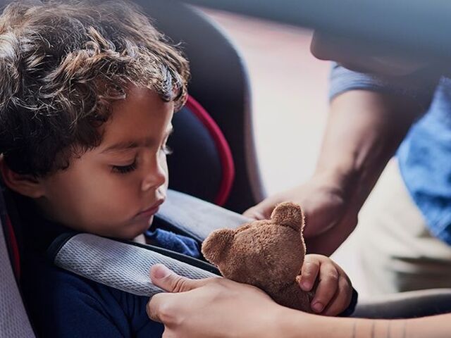 Un bimbo piccolo è posizionato nel seggiolino e allacciato.