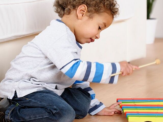 Un bimbo suona il suo xilofono colorato.