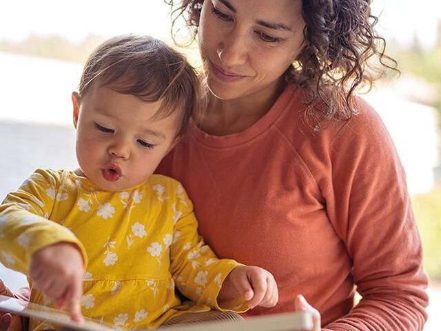 Un bimbo sfoglia un libro con la sua mamma.
