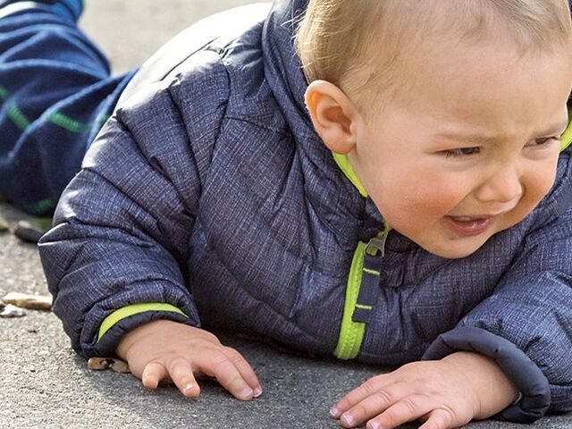 Un bimbo piccolo piange per terra.