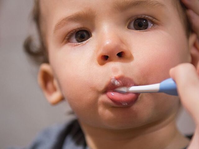 Un bimbo piccolo a cui vengono lavati i denti.