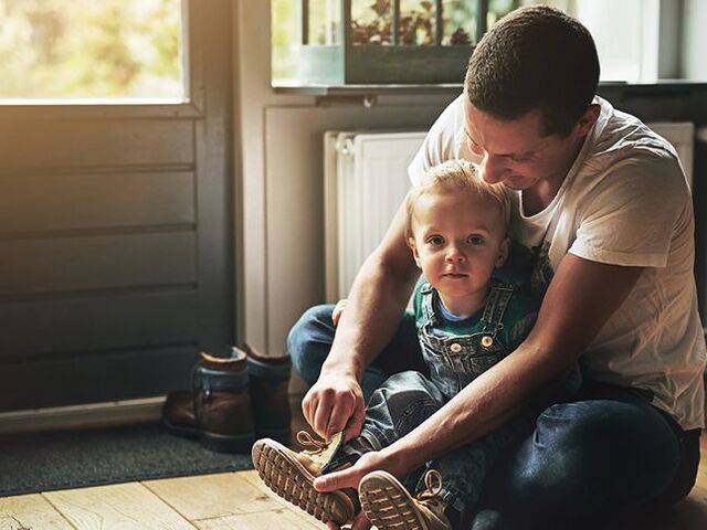 Un papà mette le scarpe al figlio.