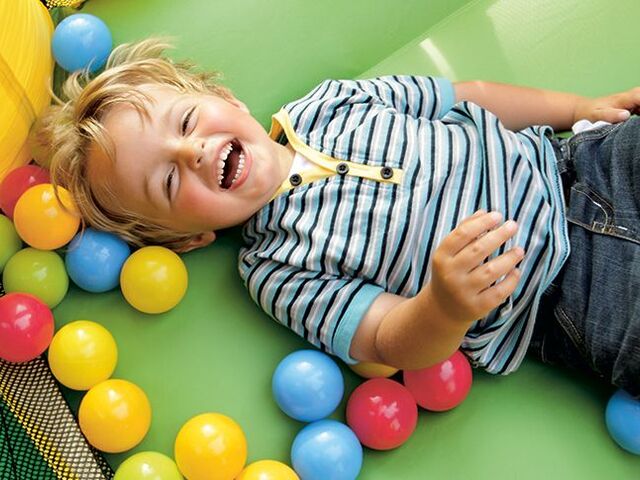 Un bimbo che ride in una vasca di palline.