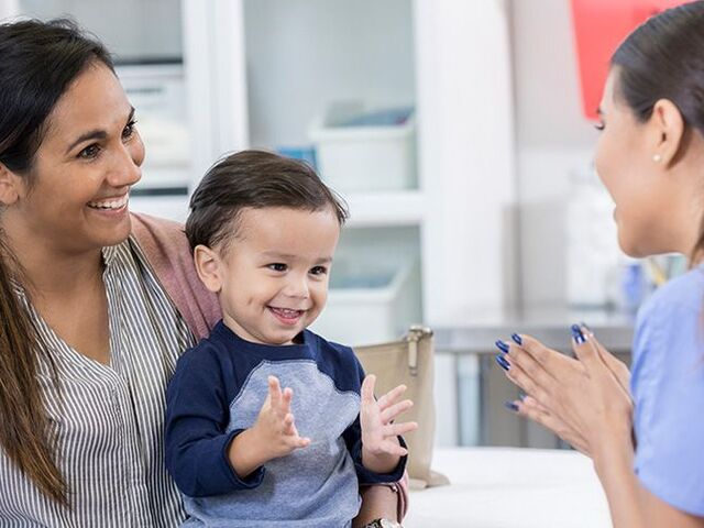 Un bimbo piccolo in grembo alla mamma in ospedale gioca con la pediatra