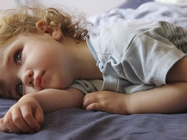 Un bimbo steso a letto con gli occhi aperti.