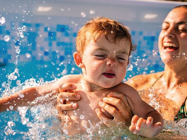 Una mamma fa il bagno in piscina con il suo piccolo.