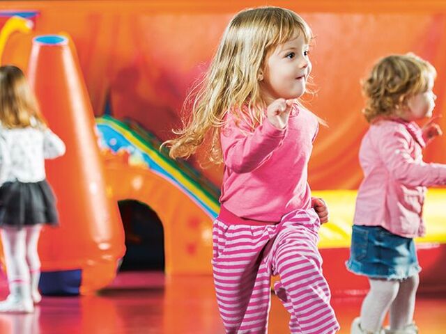 Più bimbi che camminano dentro una stanza.