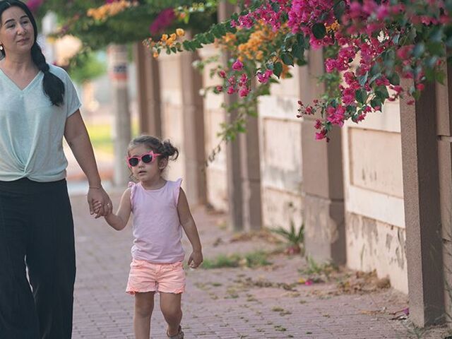 Una mamma cammina con la sua bimba sul marciapiede