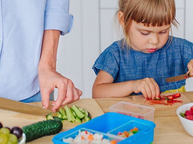 Una bimba taglia delle fragole a pezzettini.