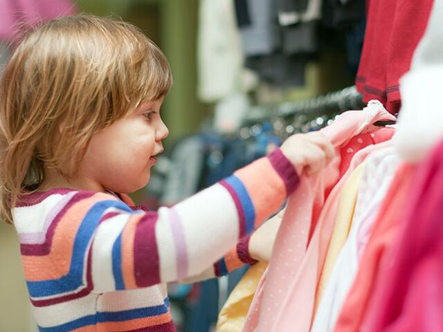 Una bimba osserva diversi vestiti in un negozio.