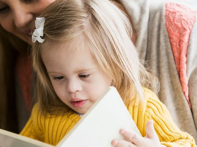 Un bimbo sfoglia un libro con la sua mamma