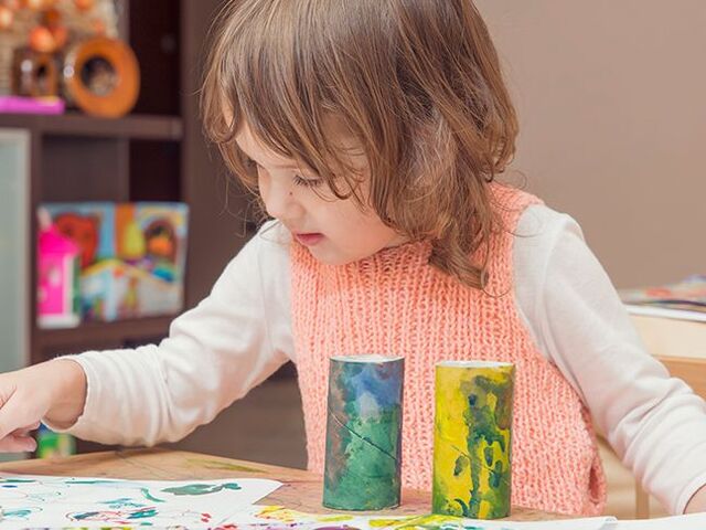 Una bimba esprime la sua creatività giocando con acquarelli e rotoli di carta igienica.