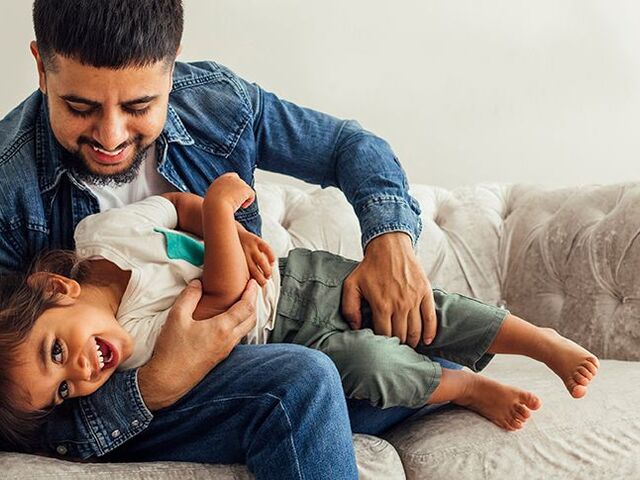 Una bimba ride mentre il papà le fa il solletico.