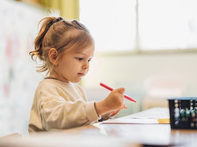 Una bimba dipinge alla scuola dell’infanzia.