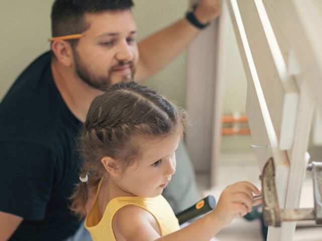 Un papà monta un letto a soppalco insieme alla figlia.