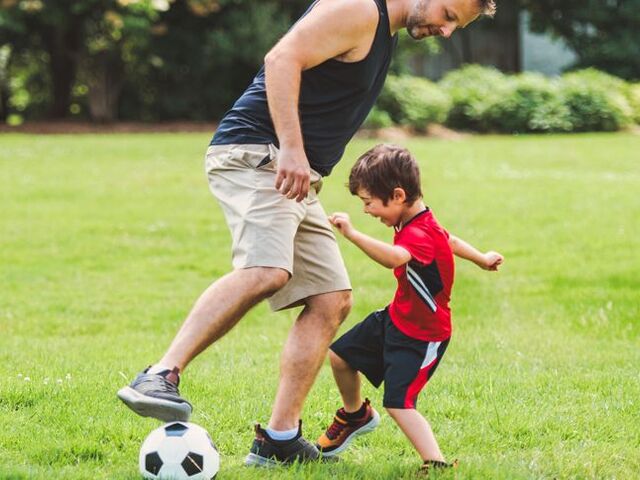 Un bimbo gioca a calcio con il papà.