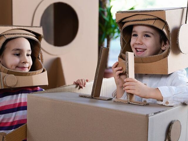 Due bimbi giocano agli astronauti dopo aver costruito razzi e tute spaziali con il cartone.