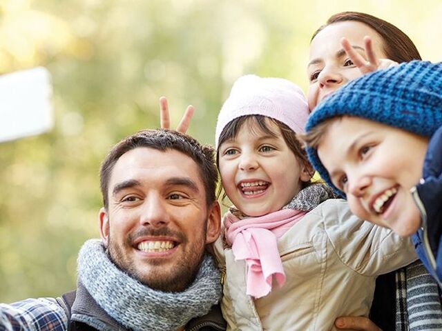 Una famiglia si scatta un selfie con lo smartphone.