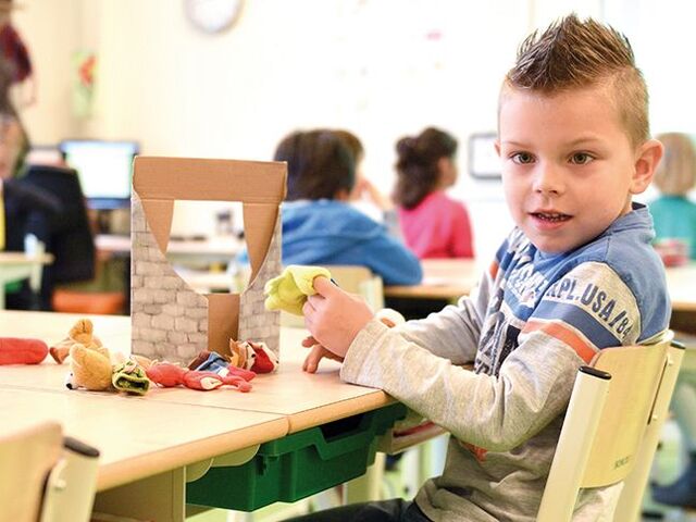 Un bimbo fa dei lavoretti in una classe.