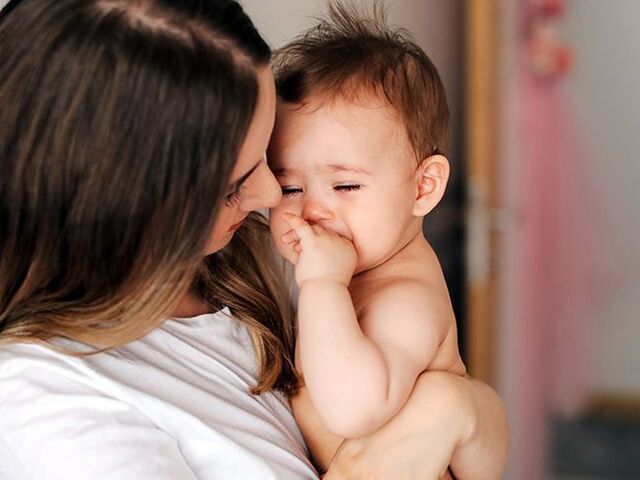 Una mamma porta in braccio il bambino che ha paura degli estranei.