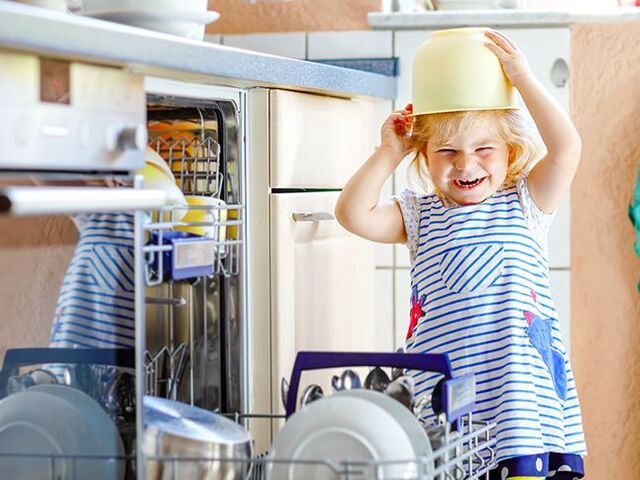 Un bambino gioca con le stoviglie della lavastoviglie.